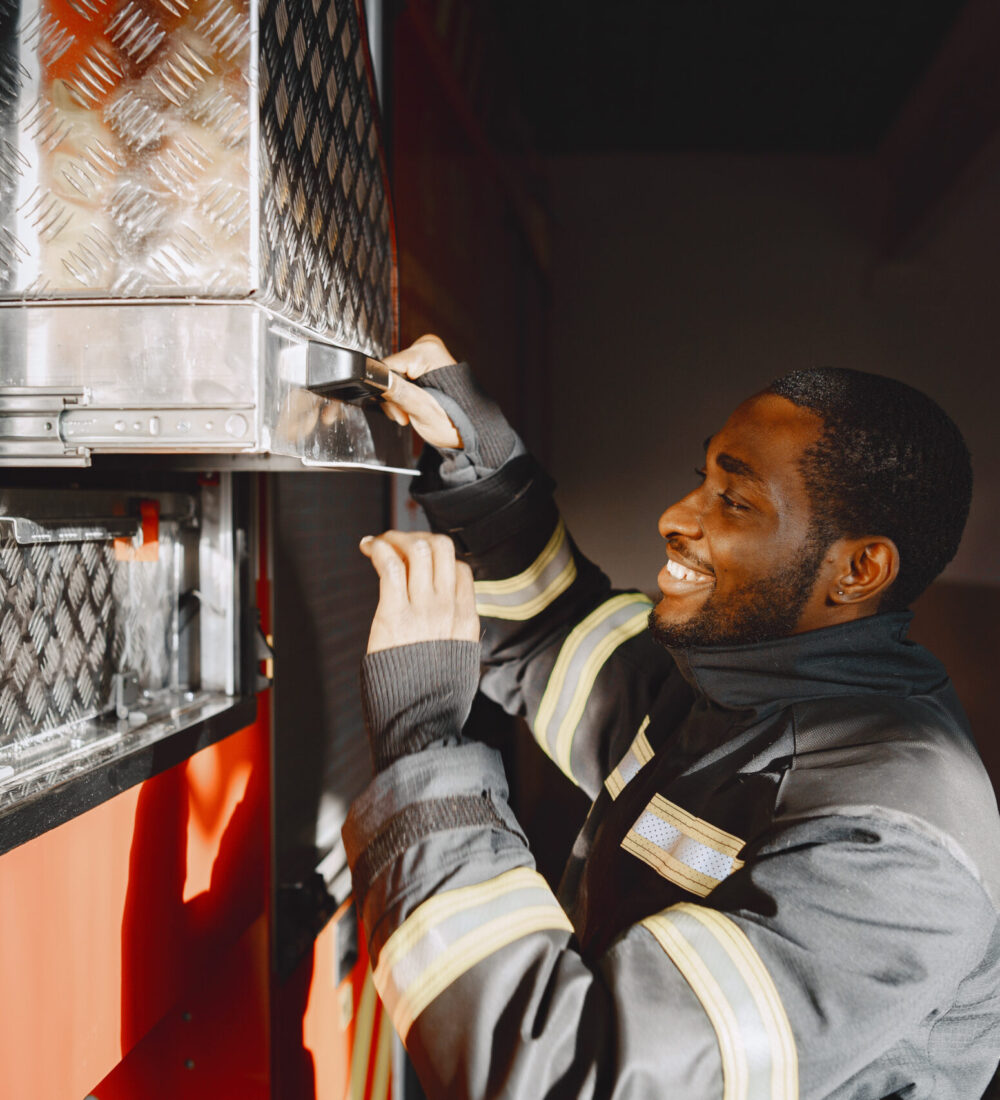 Portrait of a firefighter standing in front of a fire engine Arfican fireman in a uniform. Man prepare to work.
